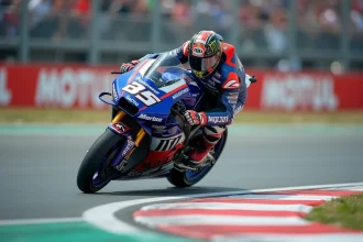 Pilote MotoGP en pleine action dans un virage sur circuit professionnel, combinaison aérodynamique et moto prototype de compétition